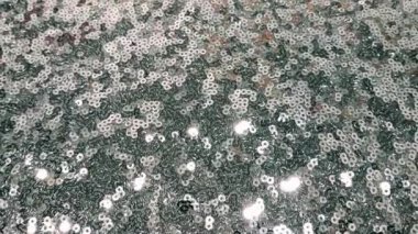 Kamera ışıltılı pullu kumaşın üzerinde süzülüyor.