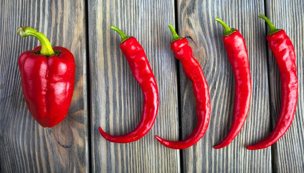 Chiles rojos picantes y pimientos sobre fondo de madera — Foto de Stock