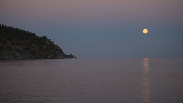 Belle scène nocturne avec la pleine lune se levant sur la mer avec un chemin lunaire .