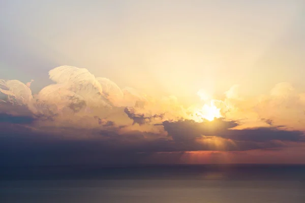 Ciel bleu avec nuages, mer et soleil à l'horizon — Photo