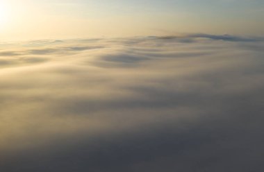 Akşam bulutlarının üzerinde uçuyor geç güneşle.