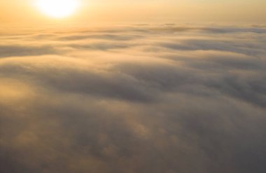 Akşam bulutlarının üzerinde uçuyor geç güneşle.