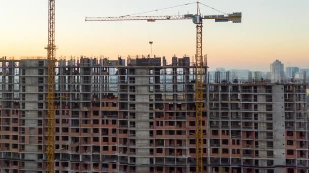 Luchtfoto van het gebouw in het bouwproces. Arbeid werkt op een grote bouwplaats. In de achtergrond Werkkraan en stad. Tijdsverloop — Stockvideo