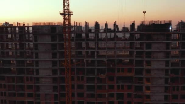 Aerial Shot of the Building in the Process of Construction. Trabajo de parto en grandes obras de construcción. En el fondo Grúa de trabajo y ciudad . — Vídeo de stock