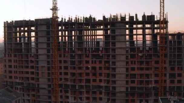 Luchtfoto van het gebouw in het bouwproces. Arbeid werkt op een grote bouwplaats. Op de achtergrond Werkkraan en stad. — Stockvideo
