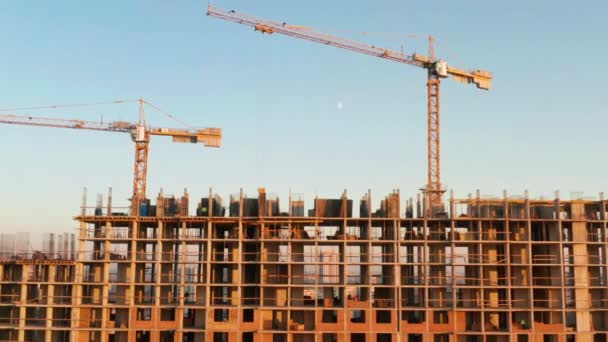 Tiro aéreo do edifício no processo de construção. Trabalho trabalhando em grande canteiro de obras. No fundo guindaste de trabalho e cidade . — Vídeo de Stock