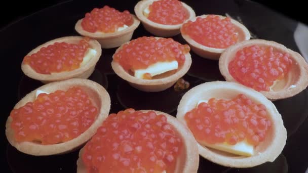 Le caviar rouge est mis avec une cuillère sur les tartelettes. Préparation de collations avec du caviar rouge. Vue de dessus. Rotation. Gros plan — Video