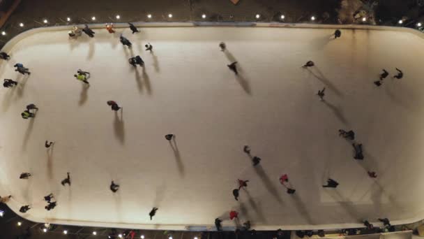 Ο κόσμος κάνει πατινάζ στο παγοδρόμιο το βράδυ. Αεροφωτογραφία κατακόρυφης κορυφής προς τα κάτω. — Αρχείο Βίντεο
