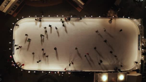人々は夕方にアイスリンクでスケートをしている。空中垂直トップダウンビュー. — ストック動画