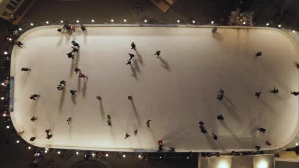 Mensen schaatsen 's avonds op de ijsbaan. Verticaal bovenaanzicht vanuit de lucht. — Stockvideo