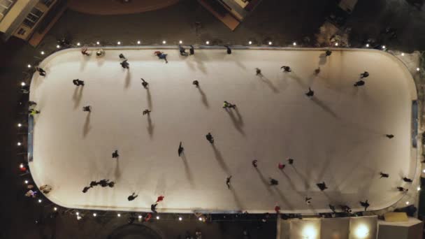 As pessoas estão patinando no ringue de gelo à noite. Vista vertical vertical vertical de cima para baixo . — Vídeo de Stock