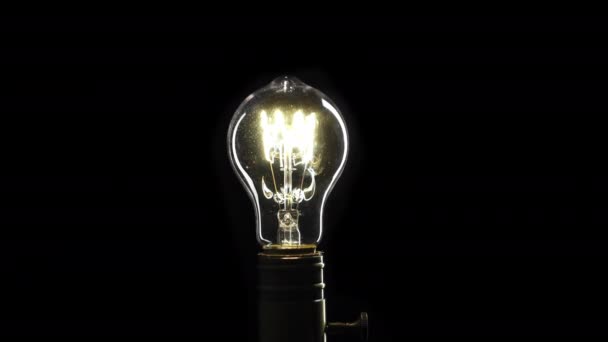 Real Edison light bulb flickering. Vintage filament Edison light bulb. Close up. 4K UHD video. Symbol of idea. The light comes on on a black background. — Stock Video
