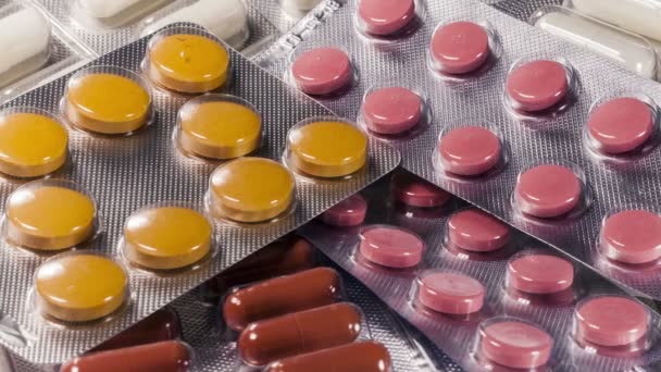 Detailní záběr různých pilulek padající na stůl s tabletami, farmaceutický průmysl koncept — Stock video