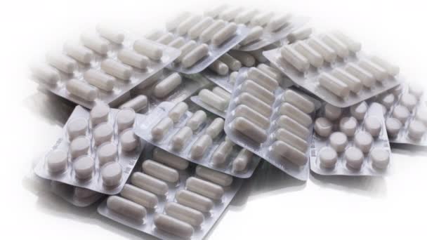 Detailní záběr různých pilulek padající na stůl s tabletami, farmaceutický průmysl koncept — Stock video