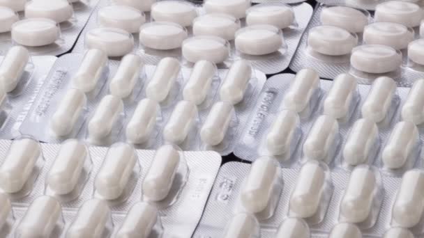 Primer plano de diferentes píldoras que caen sobre la mesa con tabletas, concepto de la industria farmacéutica — Vídeo de stock