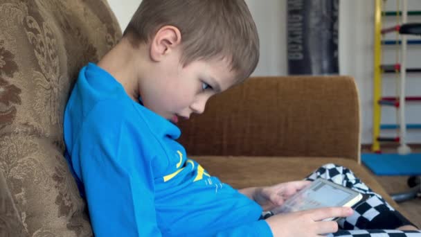 Mladý chlapec hraje videohru na dotykovém displeji tabletu. — Stock video