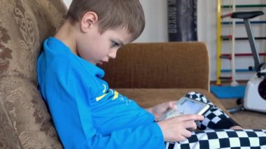 Küçük çocuk tablet dokunmatik ekranda video oyunu oynuyor.