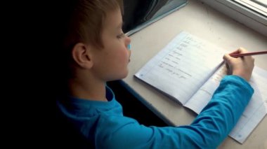 Bir çocuğun omzunun üstünden, okulda yazmayı öğreniyor.