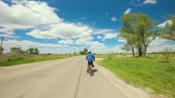 Ποδηλασία παιδιών. Νεαρό αγόρι καβάλα σε ποδήλατο με κράνος στο δρόμο στα προάστια. — Αρχείο Βίντεο