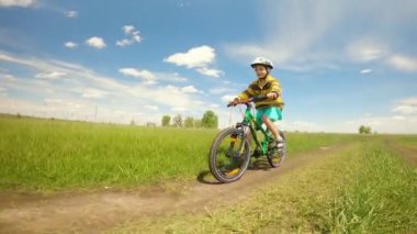 Kırsal yolda bisiklet süren küçük bir çocuk. Mutlu bir çocukluğun yaz yaşam tarzı anı.