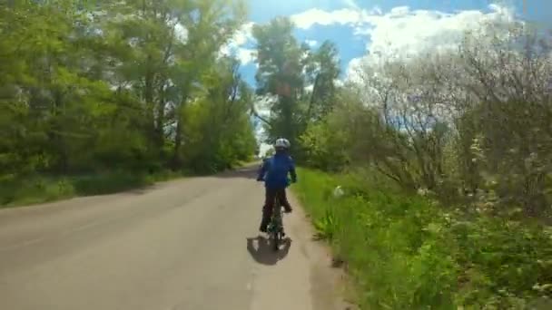 Barncykling. Ung pojke rida en cykel i en hjälm på vägen i förorter. — Stockvideo