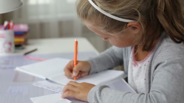 Klein schoolmeisje doet huiswerk — Stockvideo