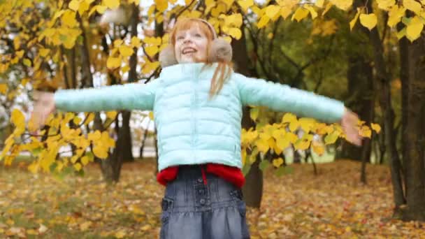 Gember meisje speelt met de herfst bladeren — Stockvideo