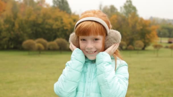 Ginger girl in the earmuffs smiling — Stock Video
