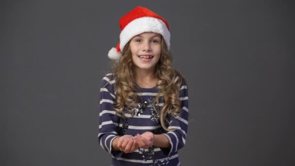 Klein meisje in een kerst muts gooien van confetti — Stockvideo