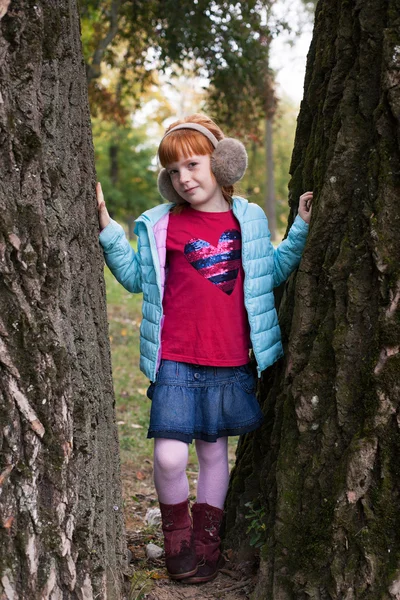 Niña pelirroja de pie entre los árboles —  Fotos de Stock