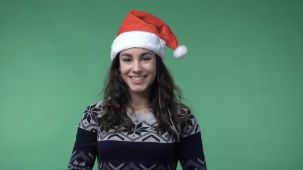 Brunette woman in a red santas cap smiling — Stockvideo