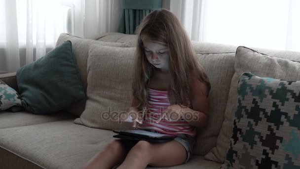 Маленькая девочка играет в игру на планшете — стоковое видео