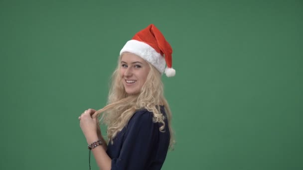 Mujer en una gorra roja de navidad sonriendo y jugando con el pelo — Vídeos de Stock