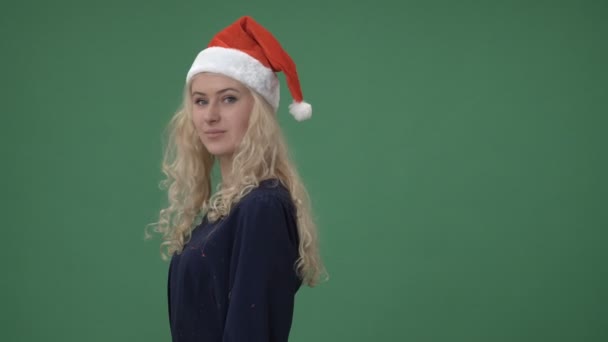 Γυναίκα σε ένα κόκκινο σκουφάκι Χριστουγέννων στροφή και χαμογελαστός — Αρχείο Βίντεο