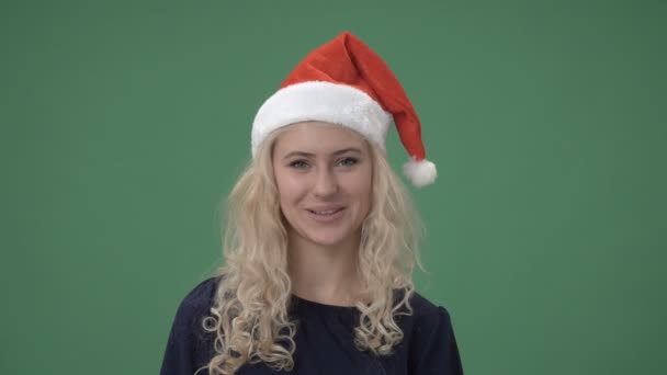 Mujer rubia en una gorra roja de santas guiñando un ojo y sonriendo — Vídeo de stock