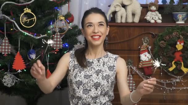 Vrouw swingende schittert tegen prachtig gekleed kerstboom — Stockvideo