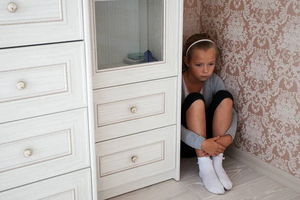 Niña triste sentada en la esquina de una habitación — Foto de Stock