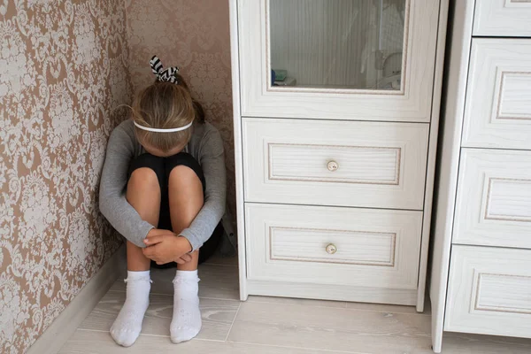 Menina triste sentada no canto de uma sala — Fotografia de Stock