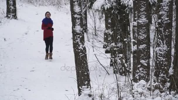 Женщина бежит в зимнем лесу — стоковое видео