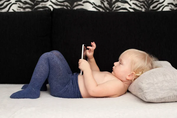 Pequeña linda chica está jugando con un teléfono inteligente — Foto de Stock