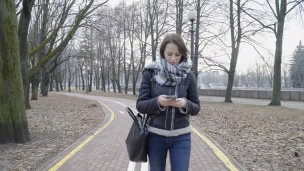 Vrouw wandelen in het stadspark met de slimme telefoon — Stockvideo