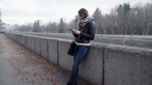 Mujer joven volteando el teléfono inteligente al aire libre — Vídeos de Stock