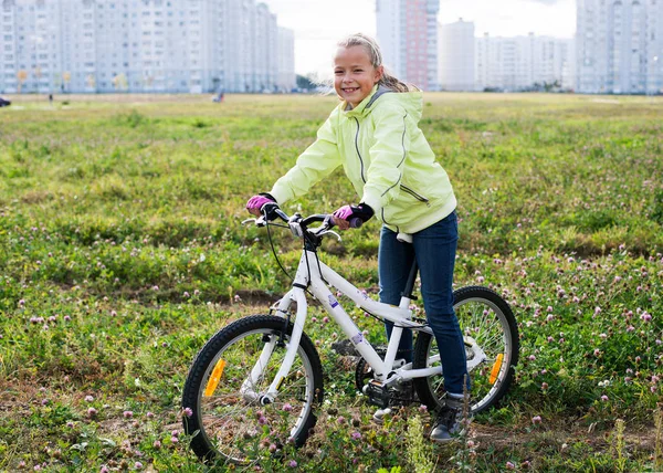 Meisje met een fiets op een groen veld — Stockfoto