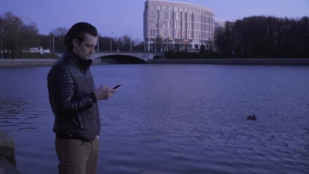 Jonge man met een smartphone in de buitenlucht — Stockvideo