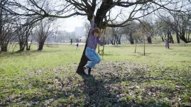 Menina de cabelos vermelhos está jogando em um parque ensolarado — Vídeo de Stock