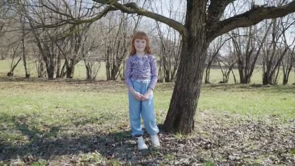 Rödhårig flicka spelar i en solig park — Stockvideo