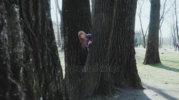 Menina de cabelos vermelhos está jogando em um parque ensolarado — Vídeo de Stock