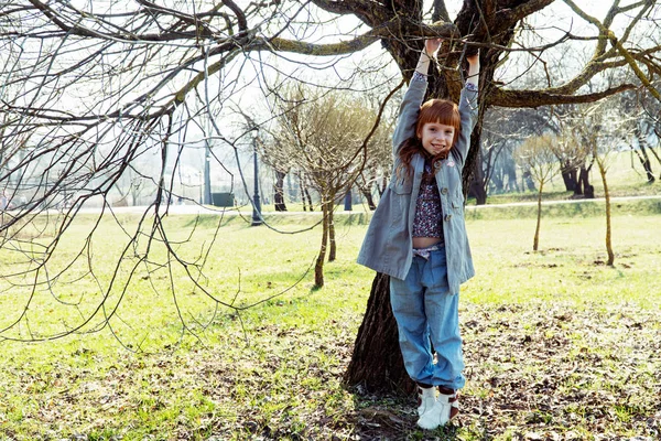 Petite fille au gingembre accrochée à un arbre — Photo
