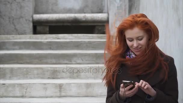 Mujer pelirroja joven con un teléfono inteligente — Vídeos de Stock