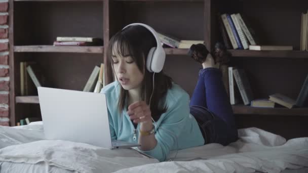 Žena v sluchátka pracují na přenosném počítači — Stock video
